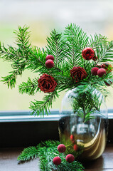 christmas composition with fir branches, artificial flowers and berries in a vase close-up.