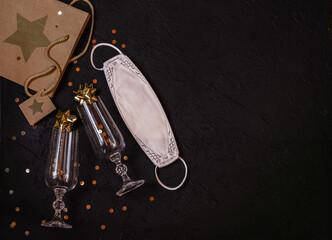 Wine glasses, gift bag, protective medical mask, gold sparkles on a black background.Place for signature.