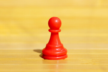 One single red pawn, solo chess piece, distinct game piece standing alone. Independence, freedom, loneliness and isolatoion abstract concept. Lone red pawn in a vast empty space, nobody, closeup