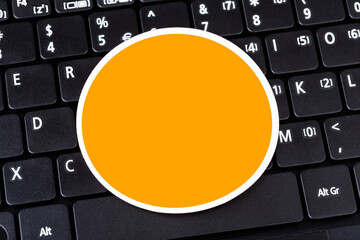 Single empty orange circle label logo space, round symbol blank sticker laying on black modern pc...