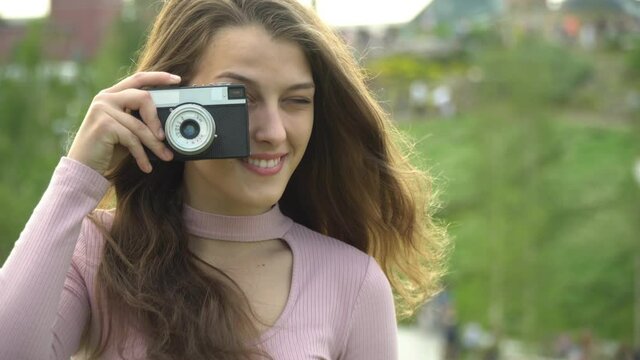 Beautiful girl with a camera taking pictures of the city