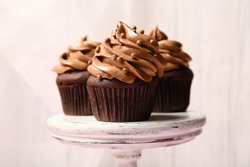 Delicious chocolate cupcakes with cream and beads on white stand, closeup