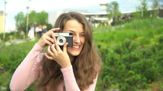 Beautiful girl with a camera taking pictures of the city