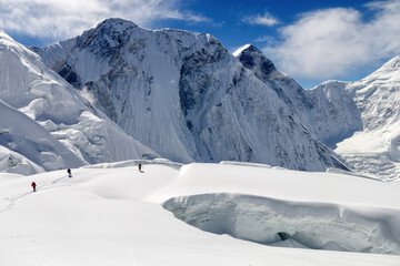 Fototapeta na wymiar Mountain climbers go around glacier crack on the background of Tengri Tau Range. Central Tian Shan, Kazakhstan - Kyrgyzstan - China.