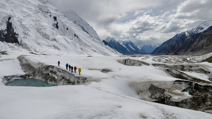 Group of mountain climbers walk above lake on North Engilchek Glacier. Central Tian Shan, Kazakhstan - Kyrgyzstan.