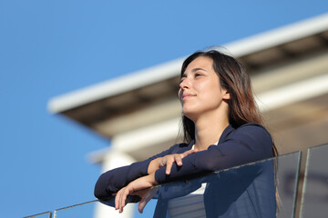 Woman contemplating views from apartment balcony