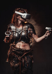 Weared with virtual reality headset scandinavian amazon with brown hairs in armour poses in dark background.
