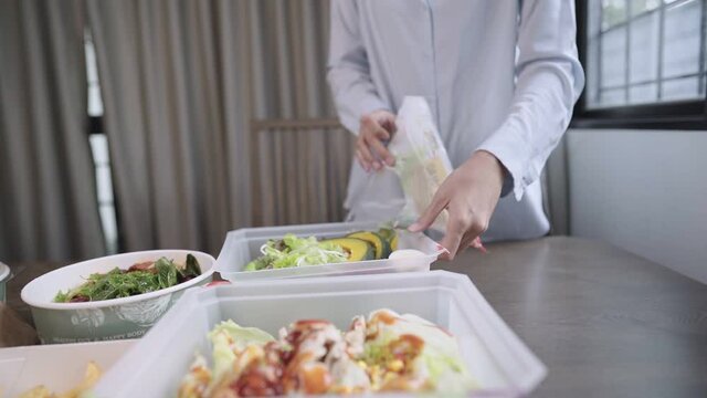 Asian woman unbox delivered food setting up table, recycle disposable food package, food Delivery service application, healthy diet Vegetables Salad, new normal take away meal during lockdown 