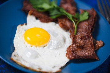 fried eggs with bacon on a blue background.