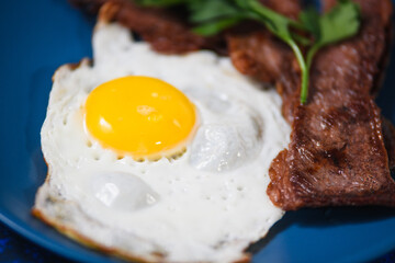 fried eggs with bacon on a blue background.