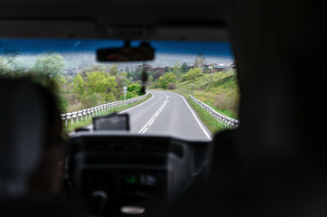 People go on vacation. Car trip to the mountains. Passenger POV at summer day on a country road, having fun driving the empty highway on tour journey.