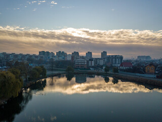 Aerial drone view. Reflection of the rising sun in the city lake.