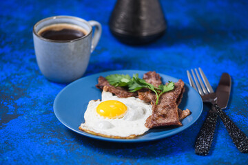 fried eggs with bacon on a blue background.