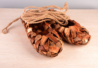 Birchen woven bast shoes hang on a log wall.