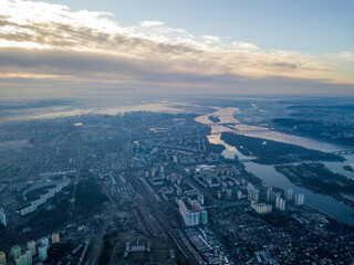 Aerial high flight over Kiev, haze over the city. Autumn morning, the Dnieper River is visible on the horizon.