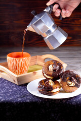 Three marshmallows in chocolate on plate, moka pot and orange cup