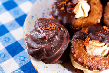 Marshmallows in chocolate on plate on a blue napkin in a white square background, closeup, horizontal