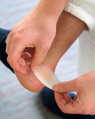 Painful Heel wound on mans feet caused by new shoes. mans hands