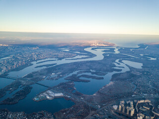 Aerial high flight over Kiev, haze over the city. Autumn morning, the Dnieper River is visible on the horizon.