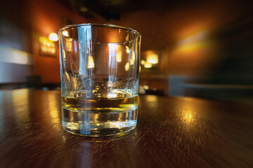 Drinking whiskey in an empty bar. Golden colour alcohol drink on wooden table in a pub. Relaxing after work, drinking booze