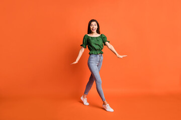 Fototapeta na wymiar Full length photo of impressed funny lady wear green off-shoulders blouse walking open mouth isolated orange color background