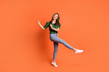 Fototapeta na wymiar Full length photo of cute adorable lady wear green off-shoulders blouse dancing isolated orange color background