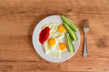 Breakfast of fried eggs and cucumbers with tomatoes.