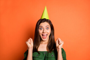 Photo of lucky lady wear green off-shoulders blouse birthday hat open mouth hands arms fists isolated orange color background
