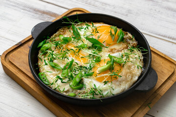 scrambled eggs with greens sprouts and green onions in a pan