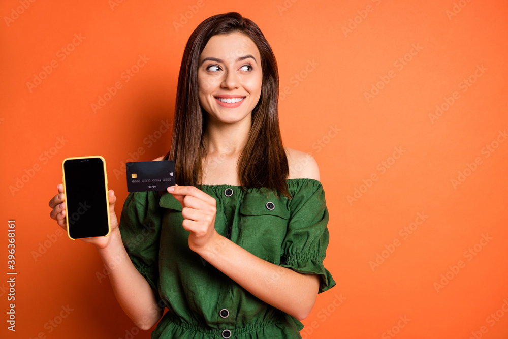 Sticker Photo of lady wear green off-shoulders blouse holding bank card modern device looking empty space isolated orange color background