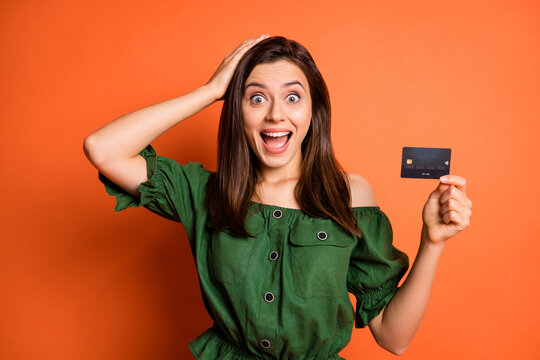 Photo of impressed funny lady wear green off-shoulders blouse arm head holding bank card isolated orange color background