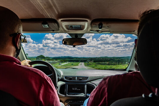 Dois homens dentro de um carro. Fotografia feita no interior do ve&iacute;culo.