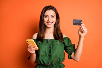 Photo of optimistic girl hold telephone card wear dark shirt isolated on orange color background