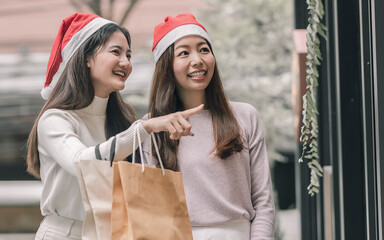 Two women doing window shopping and holding bags in christmas season