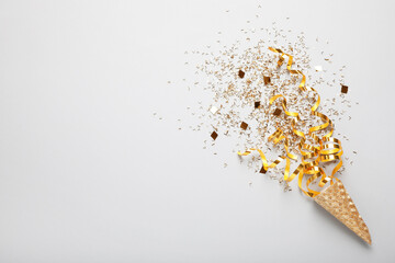Golden confetti and streamers with party cracker on white background, top view. Space for text