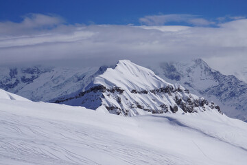 snow covered mountains with clouds and blue sky in the French Alps