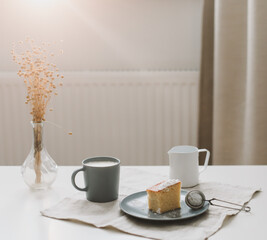Piece of homemade cake with a cup of cappuccino on table with linen tablecloth. Morning breakfast. Top view, flat lay, copy space