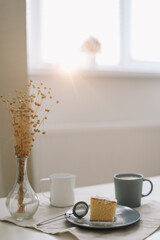 Piece of homemade cake with a cup of cappuccino on table with linen tablecloth. Morning breakfast. Top view, flat lay, copy space