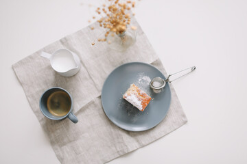 Piece of homemade cake with a cup of cappuccino on table with linen tablecloth. Morning breakfast. Top view, flat lay, copy space
