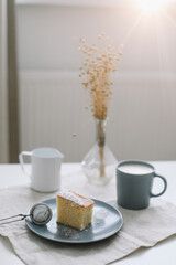 Piece of homemade cake with a cup of cappuccino on table with linen tablecloth. Morning breakfast. Top view, flat lay, copy space