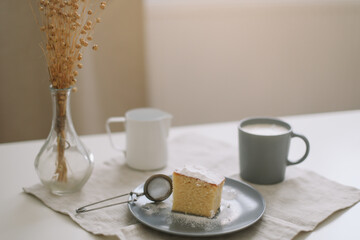 Piece of homemade cake with a cup of cappuccino on table with linen tablecloth. Morning breakfast. Top view, flat lay, copy space