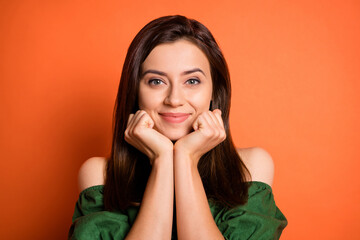 Photo portrait of cute girl wearing green blouse keeping hands near face isolated on bright orange color background
