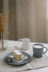 Piece of homemade cake with a cup of cappuccino on table with linen tablecloth. Morning breakfast. Top view, flat lay, copy space