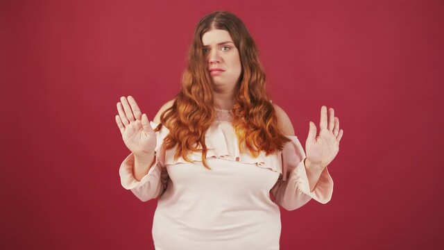 Young oversize woman listening carefully, asking ME and shaking head no, denying her involvement, red background
