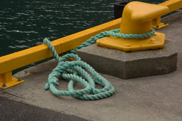 Fototapeta premium yellow bollard harbor on boat pier with green sea rope
