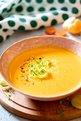 Tasty carrot creamy soup with herbs and spices in a bowl close-up. Soft focus. Autumn or winter food. Pureed vegetable soup.