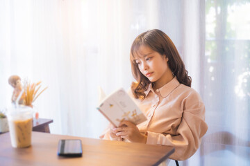 Beautiful Asian girl relaxing studying reading book casual free time weekend at café drinking coffee, social distancing feeling sad loneliness bored upset tired sleepy anxious, sitting chill careless