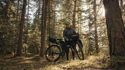 The woman travel on mixed terrain cycle touring with bike bikepacking. The traveler journey with bicycle bags. Magic forest park.