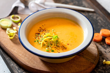 Tasty carrot creamy soup with herbs and spices in a bowl close-up. Soft focus. Autumn or winter food. Pureed vegetable soup.
