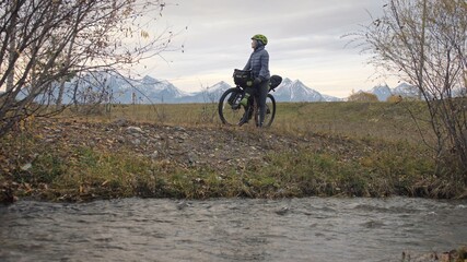 The woman travel on mixed terrain cycle touring with bikepacking. The traveler journey with bicycle bags. Sport tourism bikepacking.